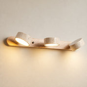 Wooden three-light wall fixture with warm glowing cylindrical spotlights.