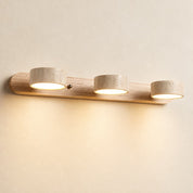 Three-light wood and stone wall fixture glowing warmly on a pale wall.