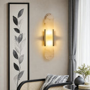 Vertical marble wall sconce with warm glow and slim bronze side bars on a neutral wall.
