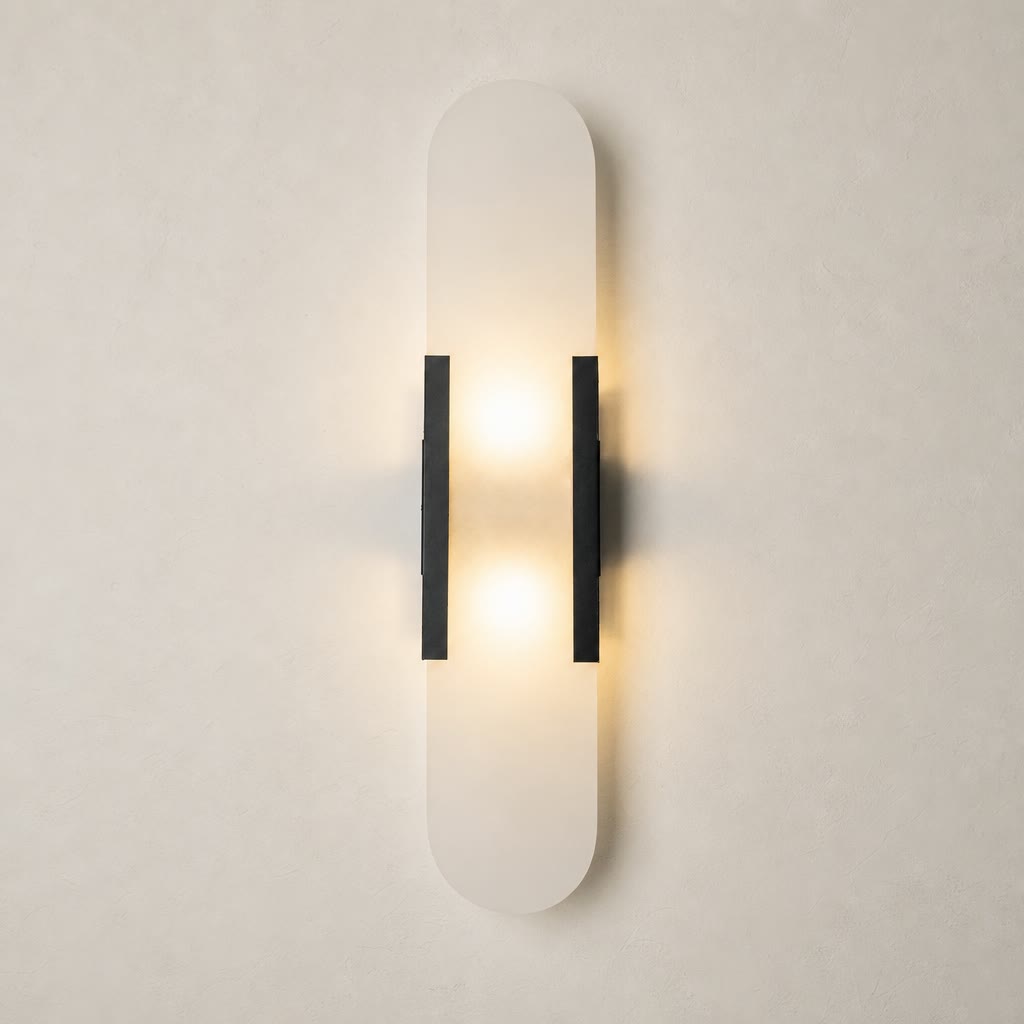 Vertical frosted wall sconce with black side brackets glowing warmly on a pale wall.