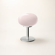 Glossy pale pink round seat on a chrome pedestal base against a clean studio background.