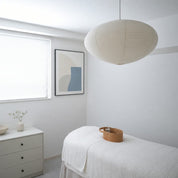 White ribbed paper pendant lamp hanging in a bright minimalist bedroom.