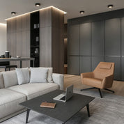 Modern living room with a beige sofa, tan lounge chair, dark coffee table, and built-in cabinets.