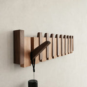 Wooden wall-mounted rail with staggered vertical blocks holding a dark angled lamp.