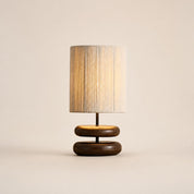 Table lamp with a beige textured shade and rounded dark wood double base.