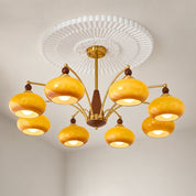 Yellow glass multi-arm chandelier with brass arms, wooden accents, and a white ceiling medallion.