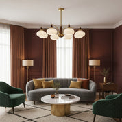Brass chandelier with six glowing white glass shades in an elegant living room.