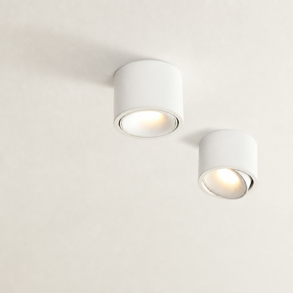 Two white cylindrical ceiling spotlights with warm recessed bulbs on a pale ceiling.