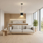 Black cube pendant light above a beige sofa in a modern living room.