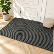 Gray striped area rug with curved line detailing on a light wood floor by a white door.