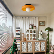 Orange flush mount ceiling light with a white globe in a cozy room.
