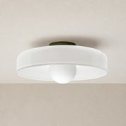 White flush mount ceiling light with a round shade and central globe diffuser.