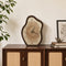 Irregular wood-grain tabletop clock with dark brown frame on a wooden cabinet.
