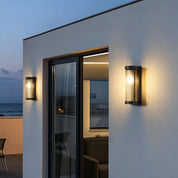 Two warm cylindrical ribbed glass wall sconces beside a modern patio doorway.
