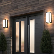 Two modern black wall lanterns illuminate a wood-sided entry with dark double doors.