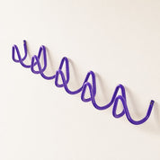Purple wavy wall-mounted rack with repeating loop hooks on a clean white background.