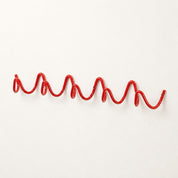 Red wavy wall-mounted coat rack on a clean white wall.