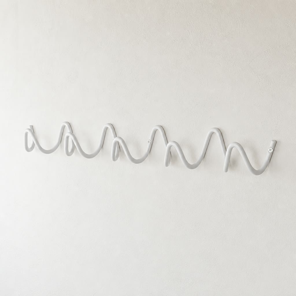 White wave-shaped wall hook rack mounted on a plain white textured wall.