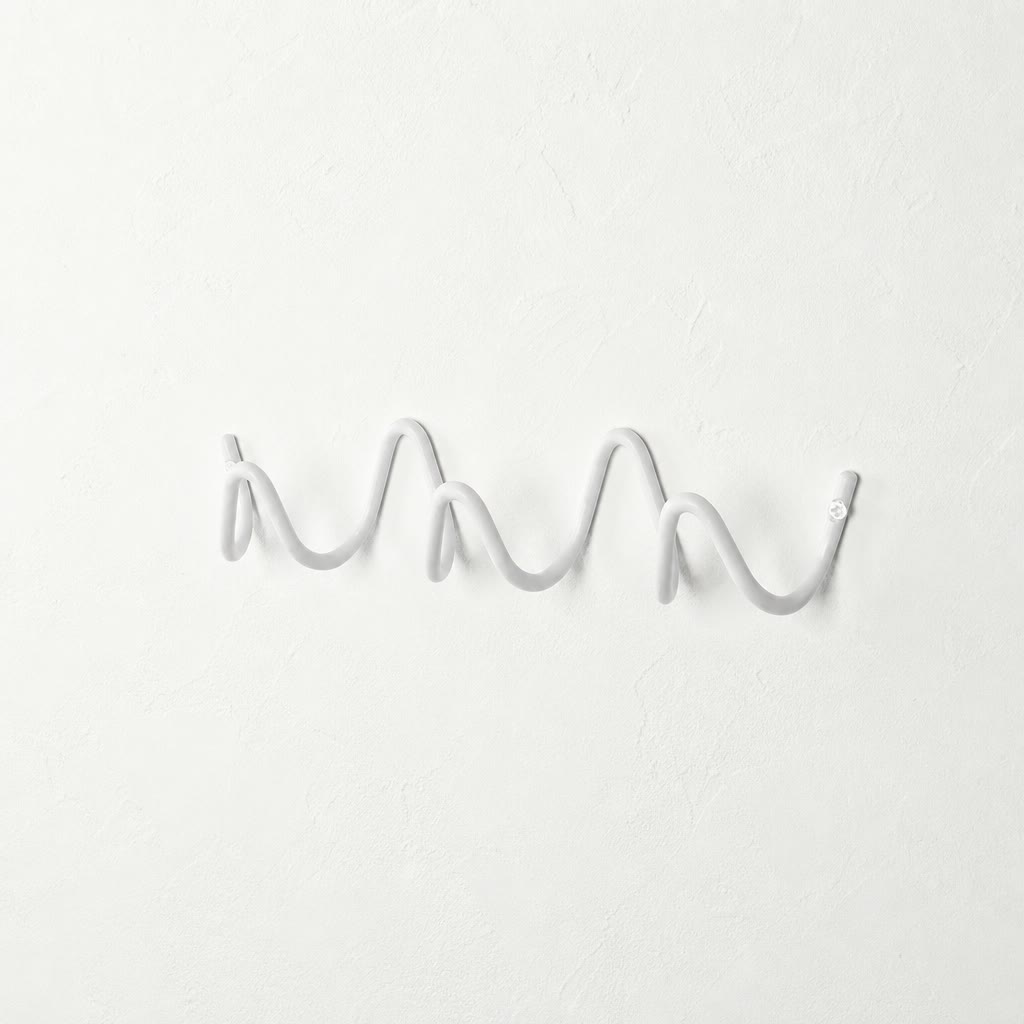 White wavy wall-mounted hook rail on a plain white textured wall.