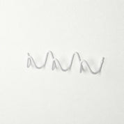 White wavy wall-mounted hook rail on a plain white textured wall.