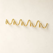 Gold wavy wall-mounted hook rack on a clean white background.