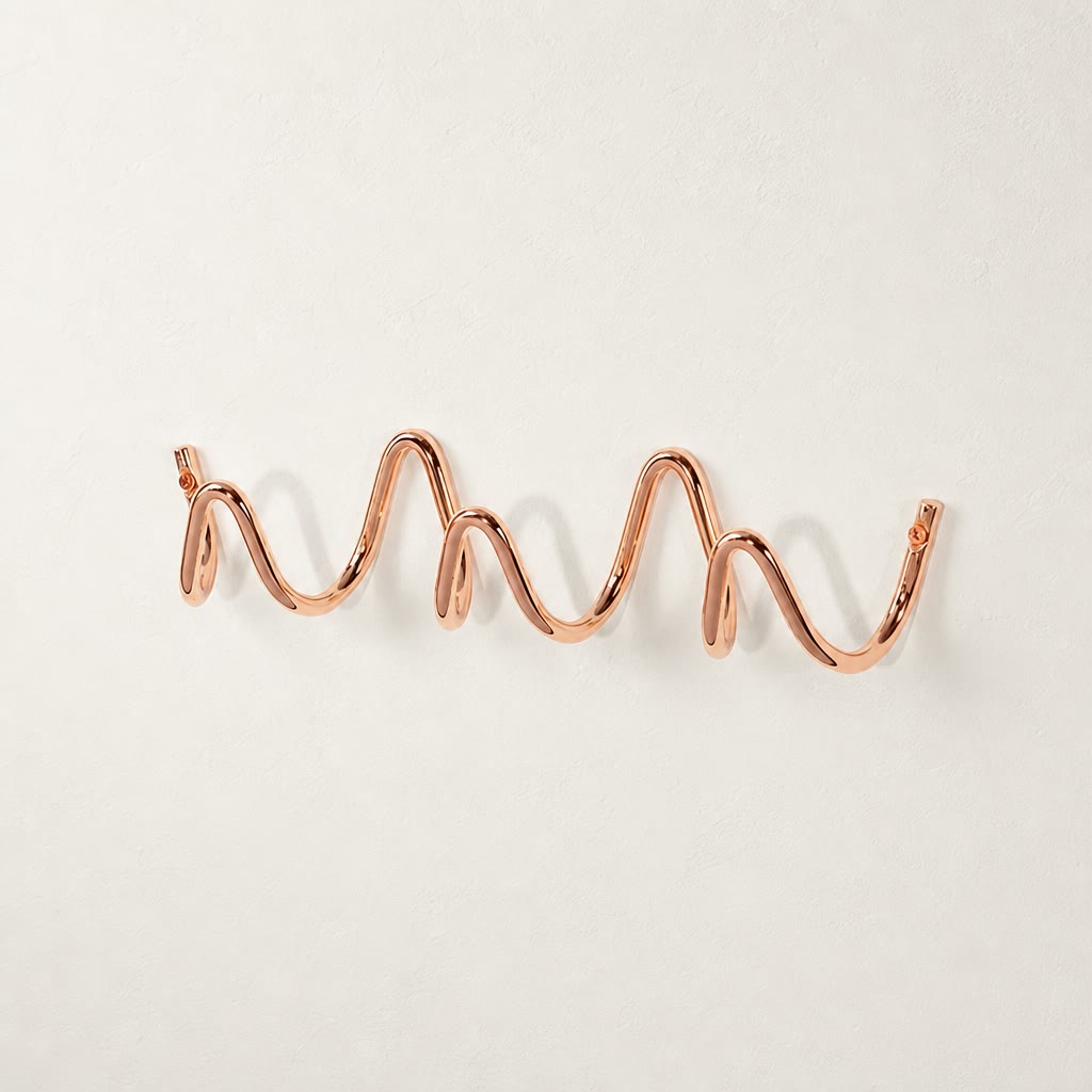 Rose gold wavy wall-mounted hook rail on a clean white surface.
