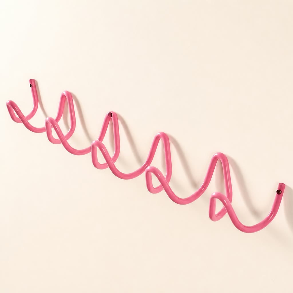 Pink wavy wall-mounted metal rack with screw holes on a plain white background.