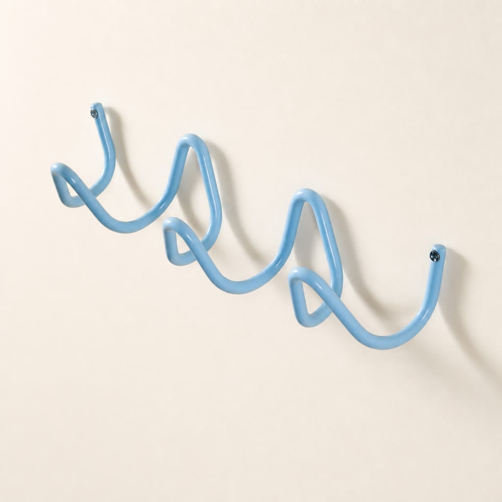 Light blue wavy wall-mounted hook rack with screw caps on a plain wall.