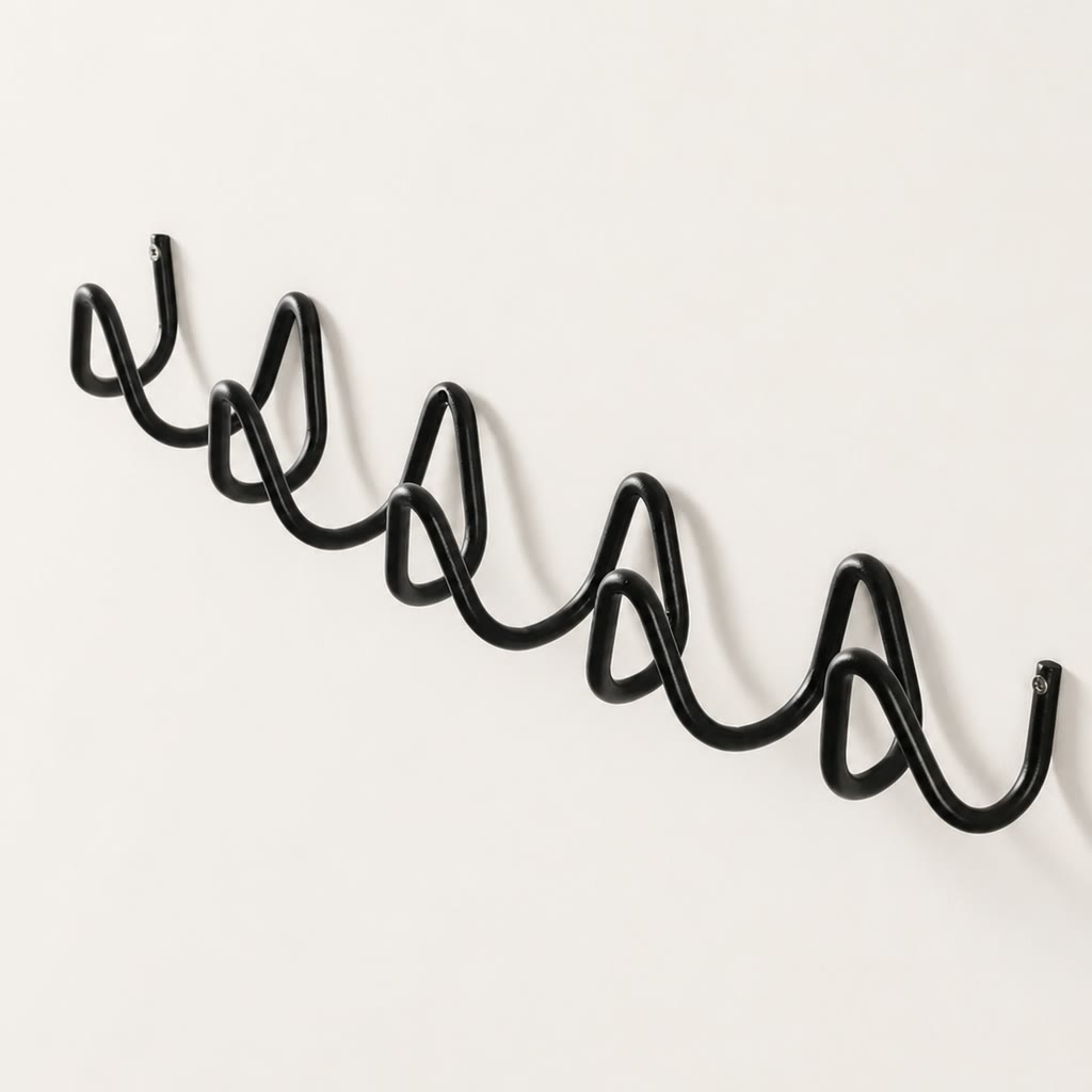Black wavy metal wall rack with multiple curved hooks on a plain light wall.