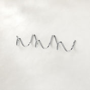 Shiny chrome wavy wall-mounted multi-hook rack on a clean light background.