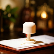 Cream mushroom-shaped table lamp on papers atop a wooden surface.
