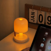 Small glowing mushroom-shaped lamp on a desk beside a calendar and tablet.