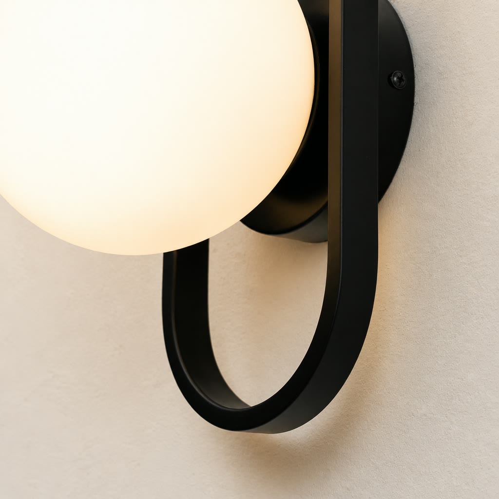 Glowing frosted globe wall sconce with black circular metal bracket on a pale textured wall.