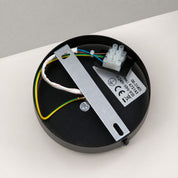 Black ceiling light mounting plate with exposed wiring, connector block, and metal bracket.