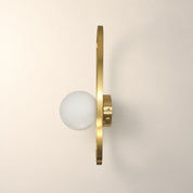 Brass wall sconce with a white glass globe and slim vertical oval frame.