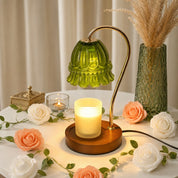 Green glass shade candle warmer lamp with wood base on a floral tabletop.
