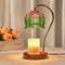 Lit candle warmer lamp with green and pink glass shade on a wooden base.