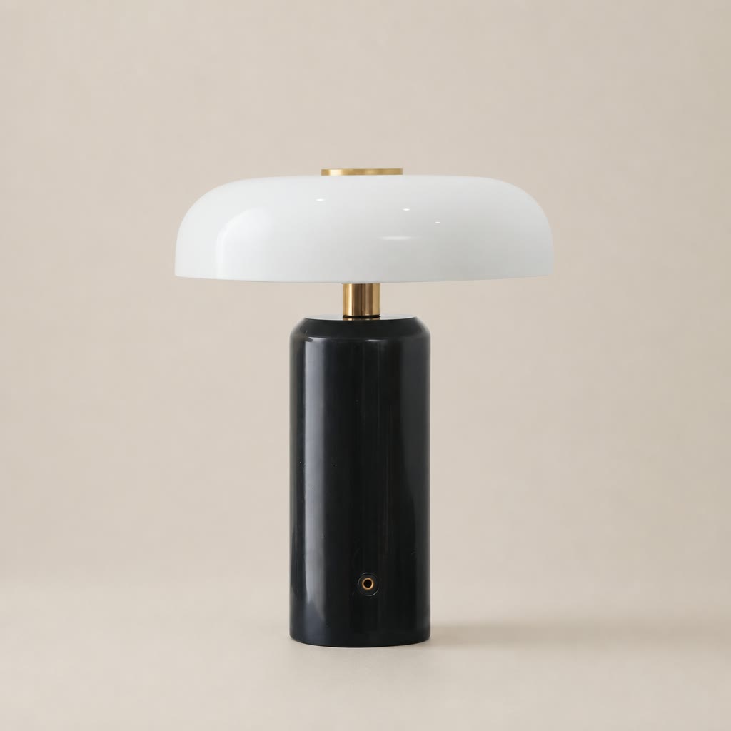Glossy black cylindrical table lamp with a white rounded shade and brass accents.
