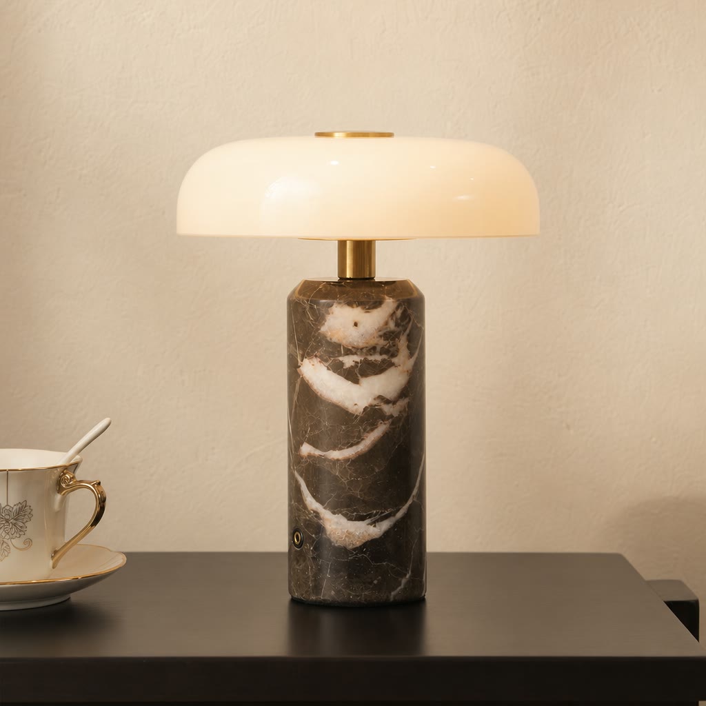 Glossy white and brass lamp with a dark marble cylinder base on a side table.