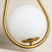 Frosted white globe light held in a brushed gold teardrop-shaped metal frame.