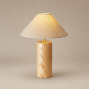 Wooden table lamp with beige fabric shade and warm glow on a neutral studio background.