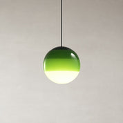 Green glass globe pendant light hanging from a black cord against a pale minimalist wall.