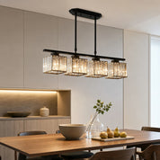 Black four-light crystal pendant chandelier above a modern wooden dining table.