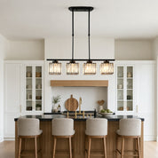 Four-light black linear chandelier with glowing crystal shades over a kitchen island.