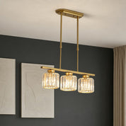 Gold three-light linear pendant chandelier with ribbed glass shades hanging from a ceiling.