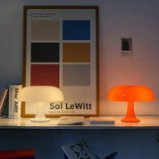 Glossy cream and orange mushroom table lamps glowing on a shelf.