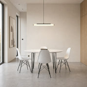 Linear black pendant light glows above a round marble dining table with white chairs.