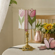 Pink tulip stained glass table lamp with an ornate gold base on a table.