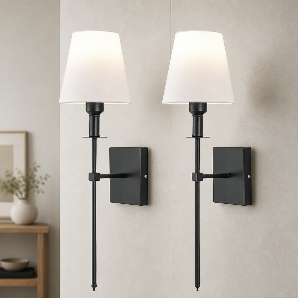 Two black wall sconces with white fabric shades mounted on a light gray wall.