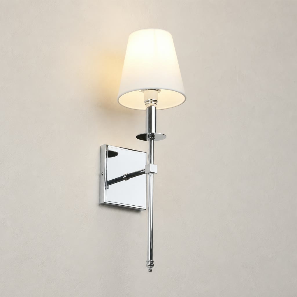Chrome wall sconce with a glowing white fabric shade on a light neutral wall.